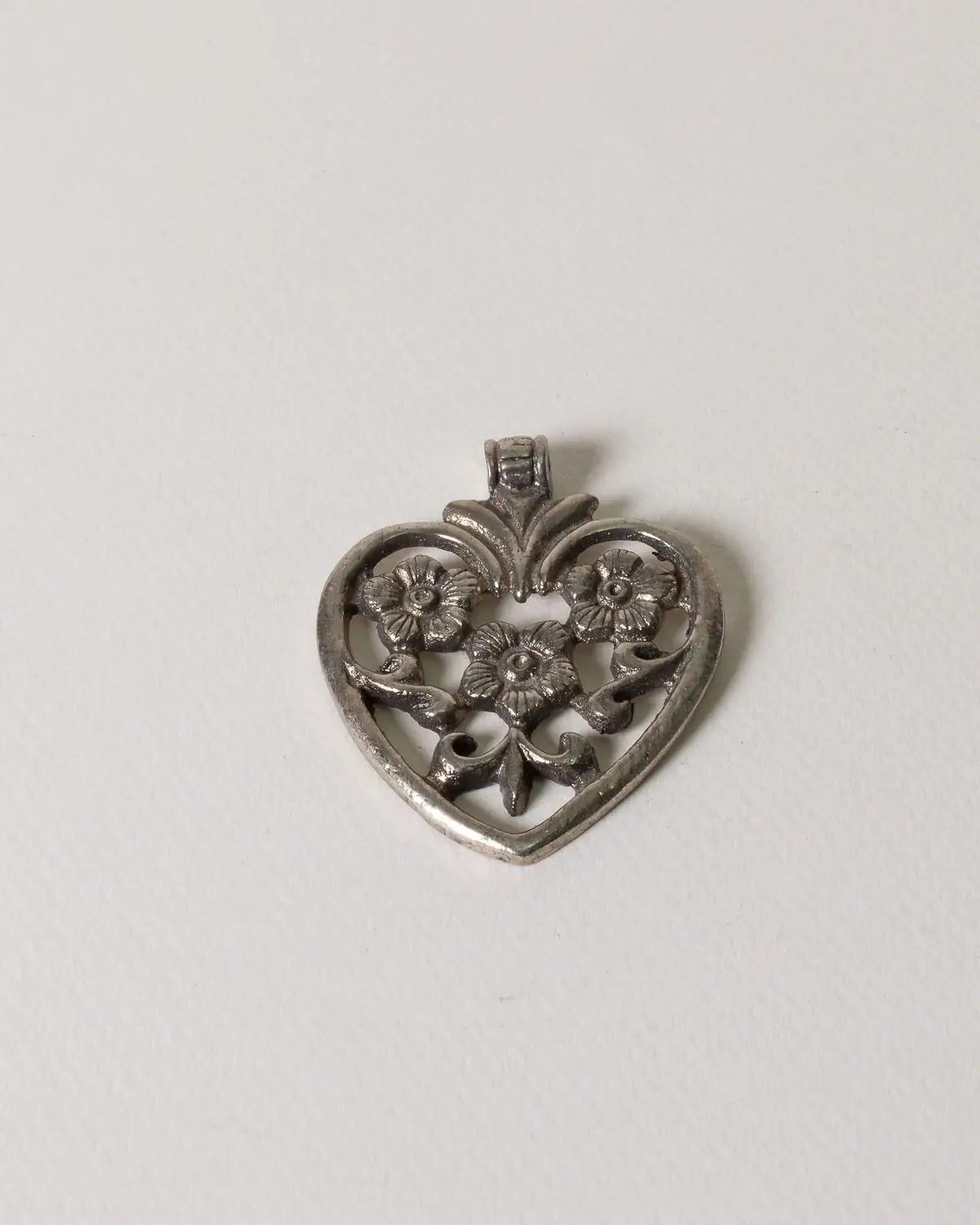 Corazón de bronce con tres flores dentro. Plateado
